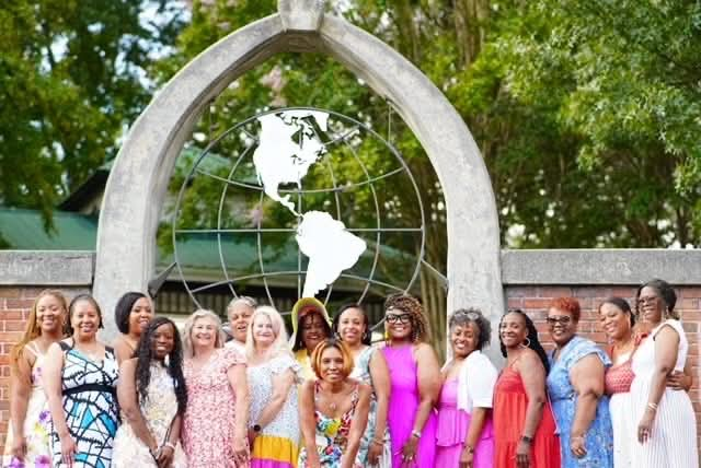 Camisha with a large group of women beneath a globe sculpture