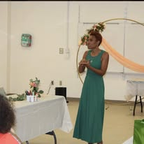 Camisha speaking in a green dress at an indoor event